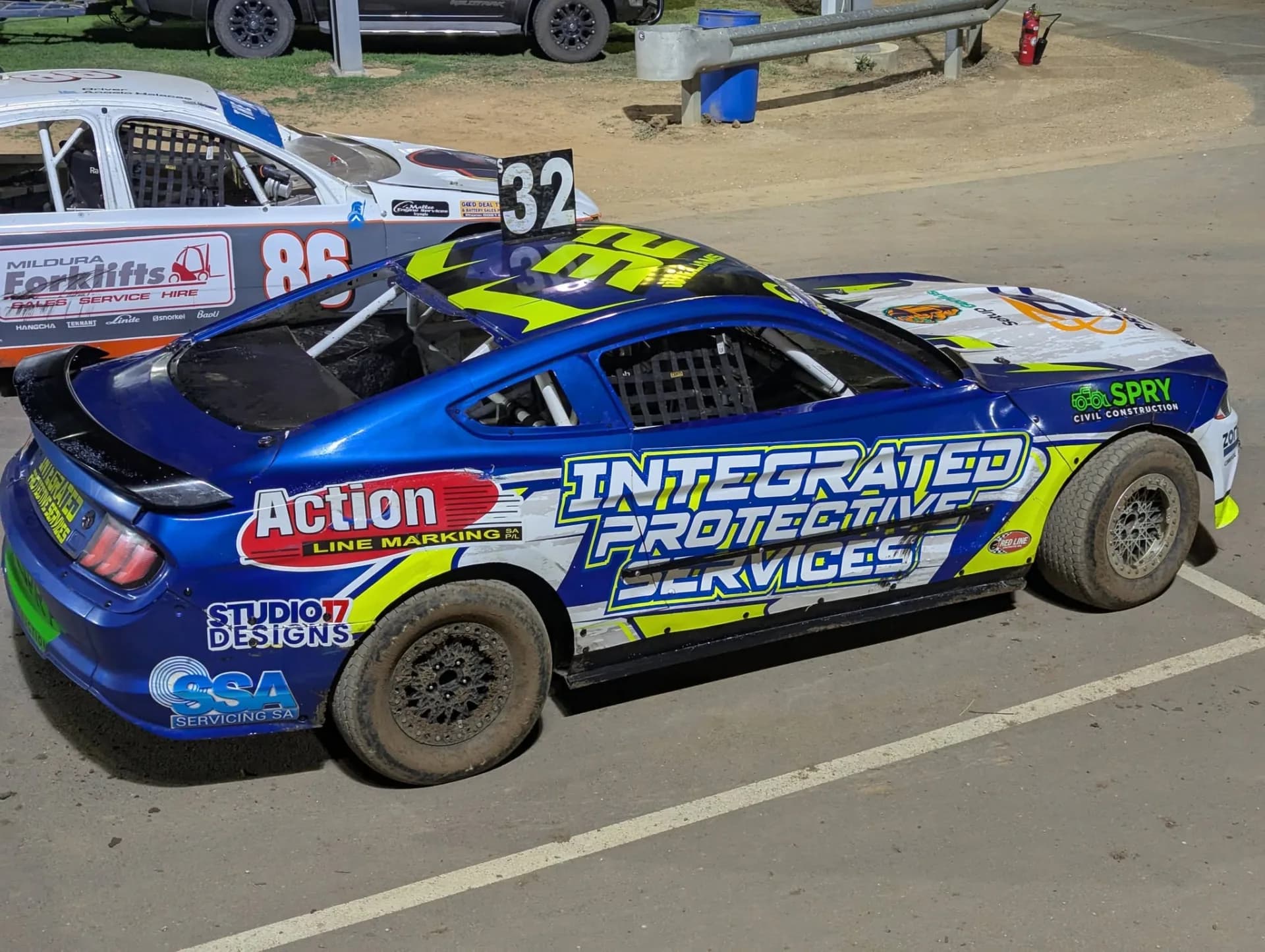 #32 WRT Mustang rear three-quarter view, battle-worn in the night pits